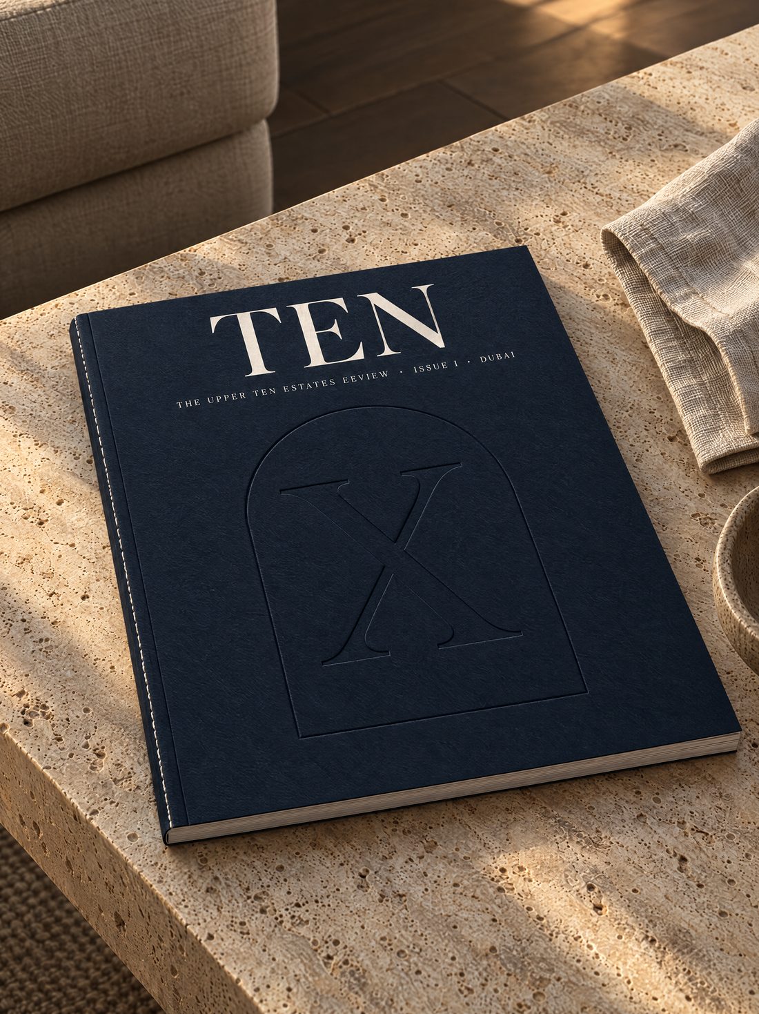 The cover of TEN, a navy magazine with a blind-debossed X inside an arch